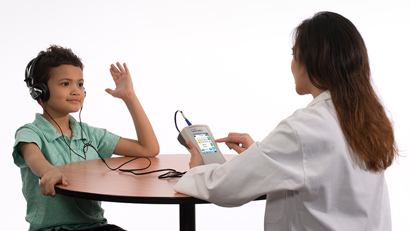 Clinician performing hearing assessment using Bio-logic AuDX PRO portable audiometry tool.