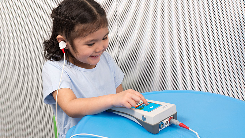 Child interacting with the Bio-logic AuDX Portable OAE Screening Device during a Pure Tone Audiometry Screening session.