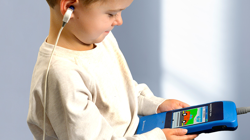 Child using Madsen Alpha Handheld OAE Screener during preschool hearing screening.